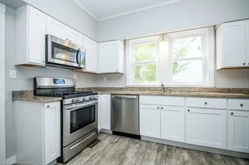 a kitchen with granite countertop white cabinets appliances and a large window