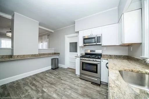 a kitchen with stainless steel appliances granite countertop a stove a sink and a microwave