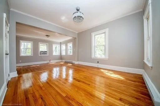 a view of an empty room with window and wooden floor
