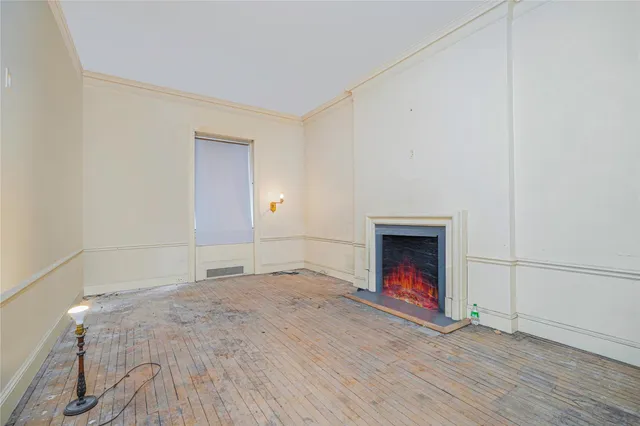 an empty room with wooden floor fireplace and windows