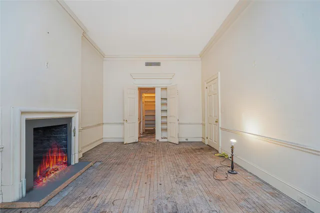 an empty room with wooden floor fireplace and windows
