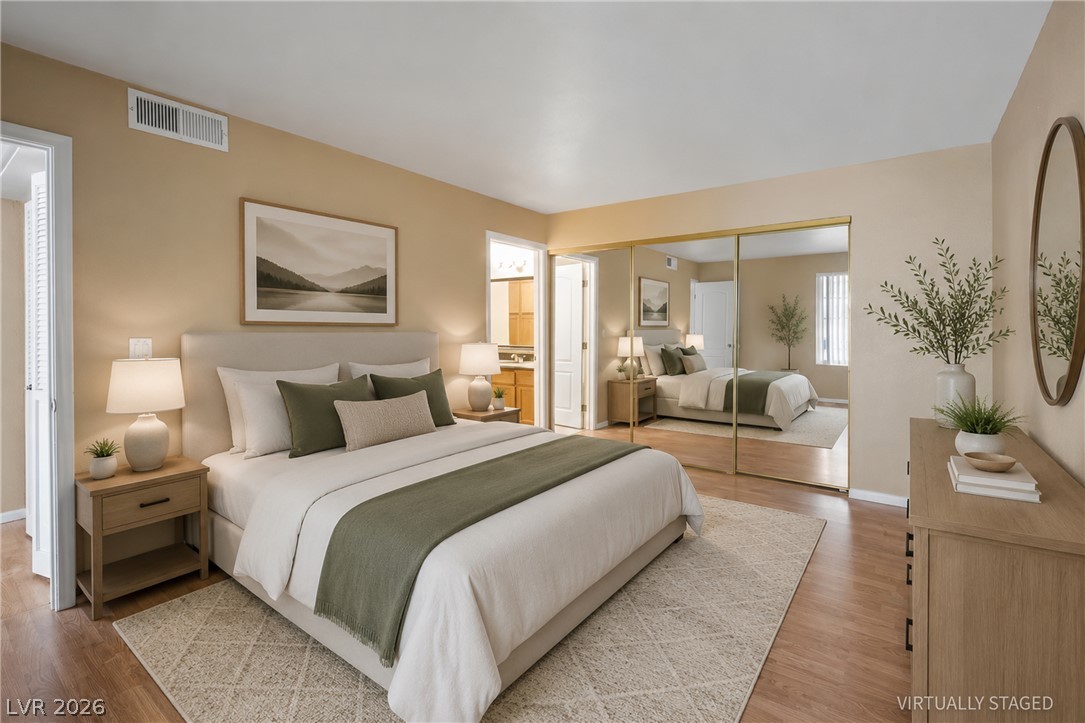 Hardwood floors and a spacious mirrored closet define this serene bedroom, offering both comfort and practical elegance.