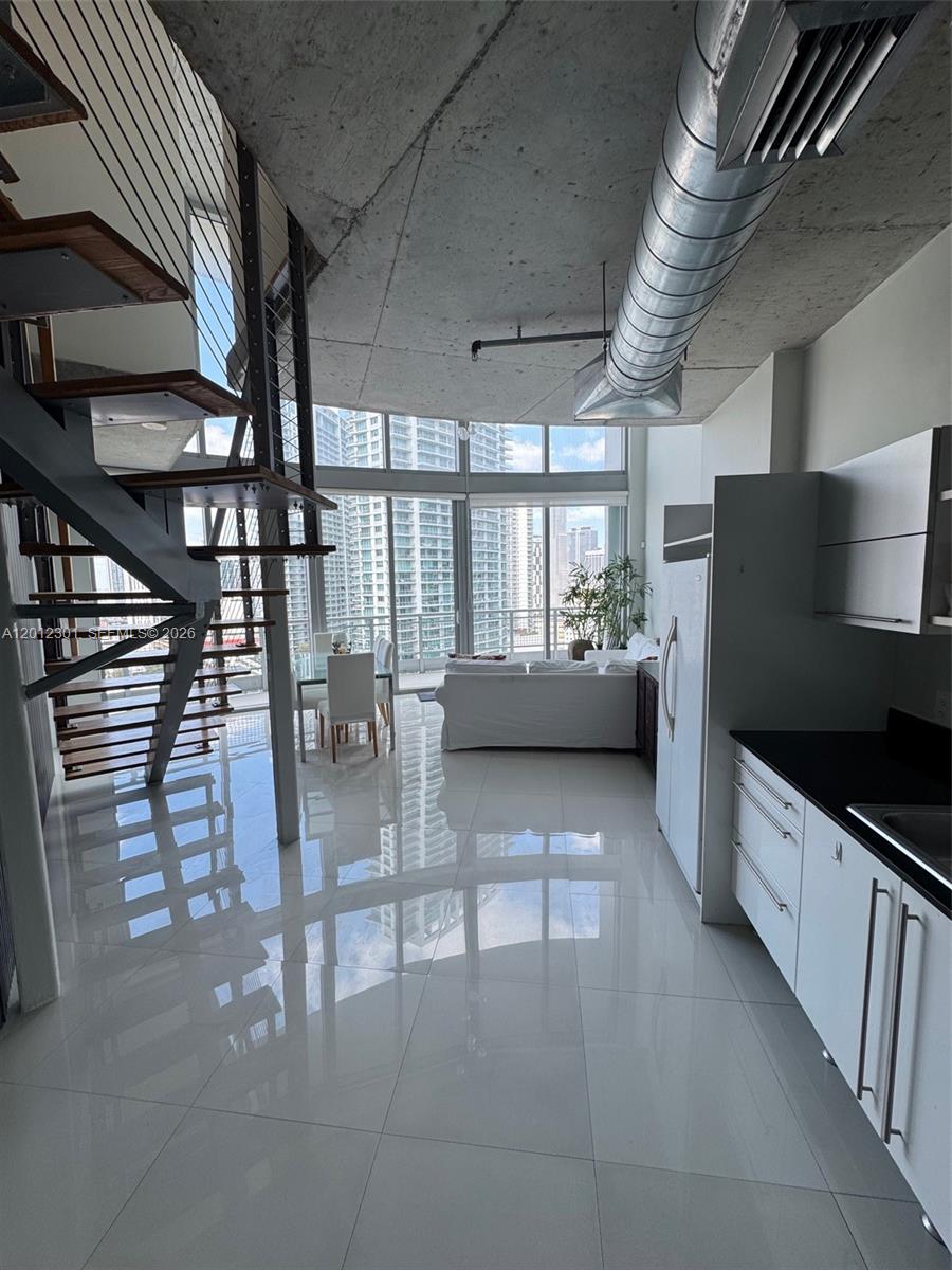 690 Southwest 1st Court, Unit 2301 Miami, FL 33130 - Photo 12 of 26 a kitchen with stainless steel appliances granite countertop a table chairs and a refrigerator
