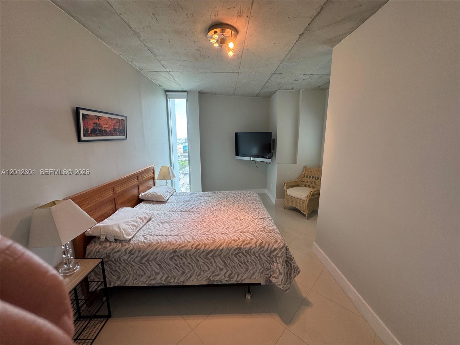 690 Southwest 1st Court, Unit 2301 Miami, FL 33130 - Photo 20 of 26 a bedroom with a bed window and a flat screen tv