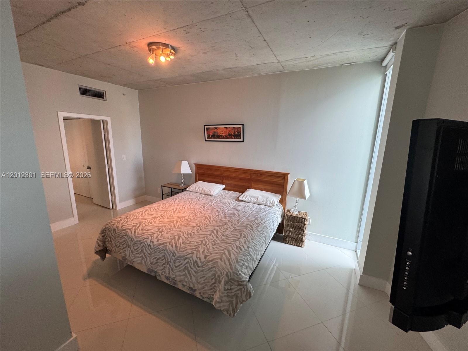 690 Southwest 1st Court, Unit 2301 Miami, FL 33130 - Photo 21 of 26 a bedroom with a bed and a lamp on desk