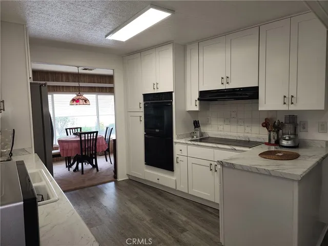 a kitchen with stainless steel appliances kitchen island granite countertop a refrigerator a sink a stove and white cabinets