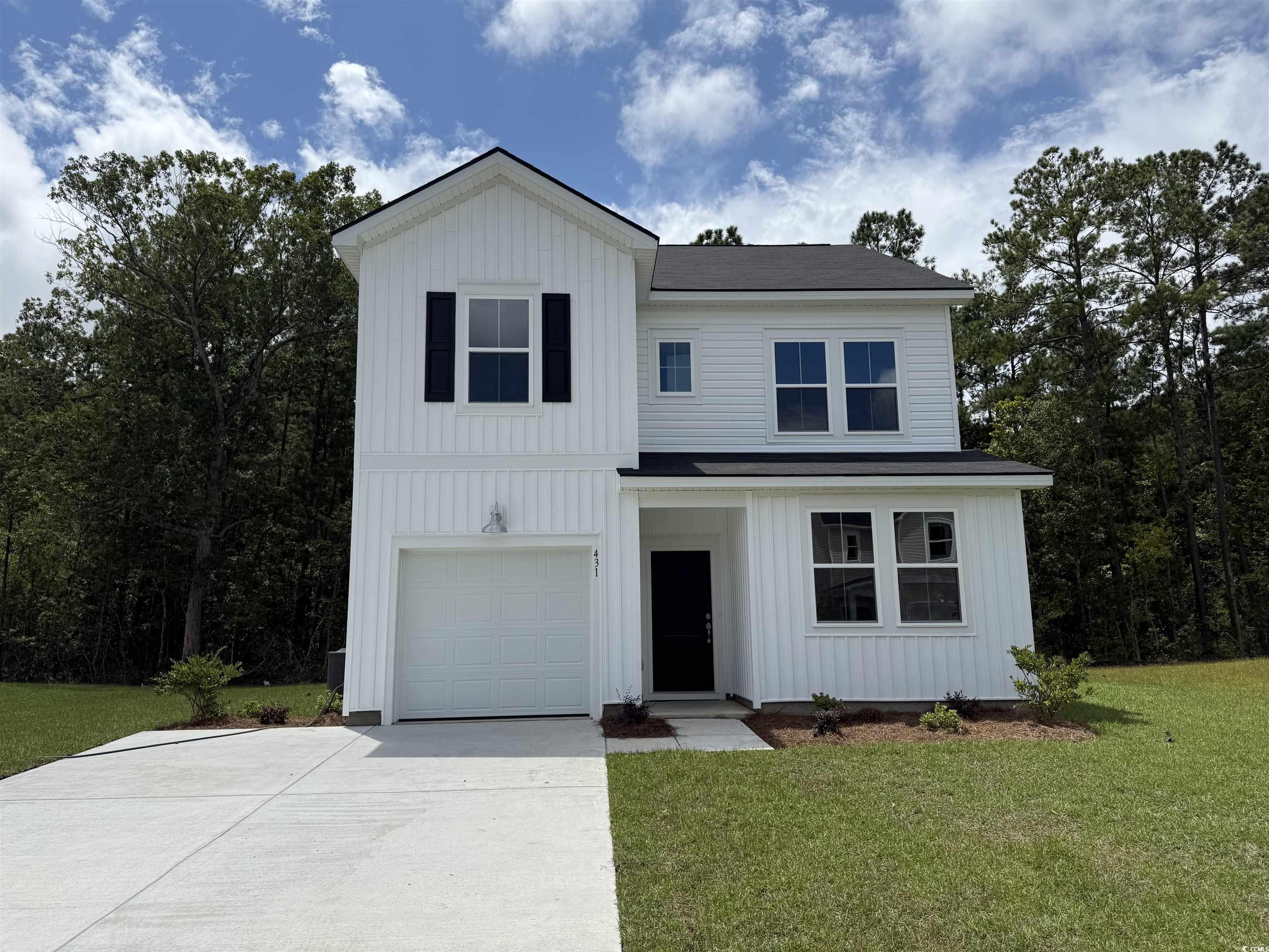 Modern farmhouse featuring board and batten siding, a front lawn, driveway, and a garage