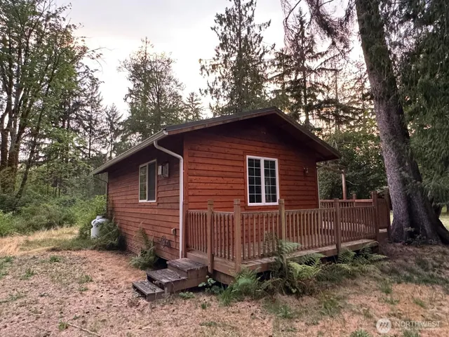 a view of a small house with a yard and large trees
