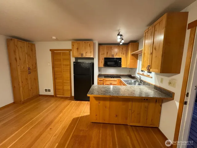 a kitchen with kitchen island granite countertop wooden floors and stainless steel appliances