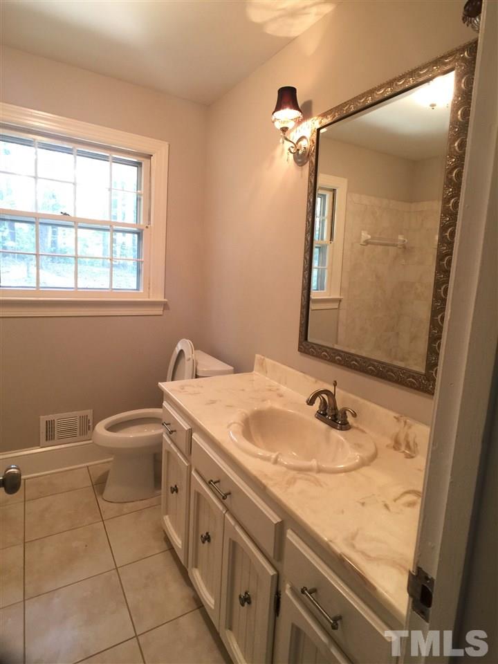 3105 Braddock Drive Raleigh, NC 27612 - Photo 18 of 19 a bathroom with a granite countertop sink a toilet and a mirror