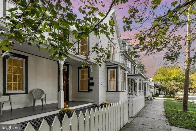 a front view of a house with large trees