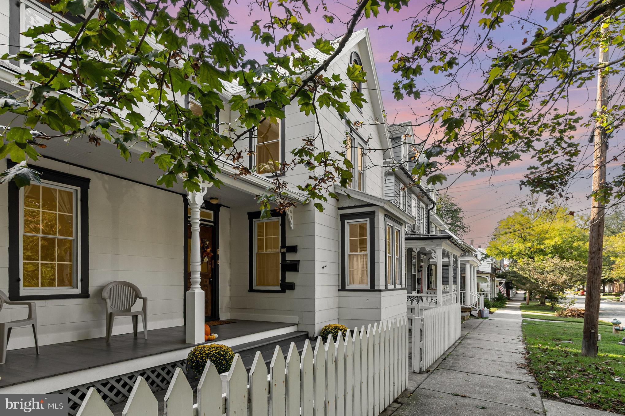 a front view of a house with large trees