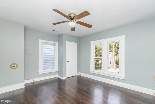 an empty room with wooden floor chandelier fan and windows