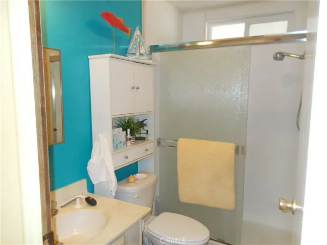 a white toilet sitting next to a bathroom sink and a shower