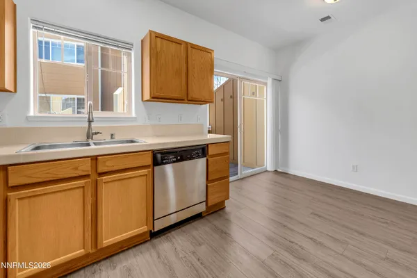 a kitchen with stainless steel appliances granite countertop a sink and wooden cabinets with wooden floor