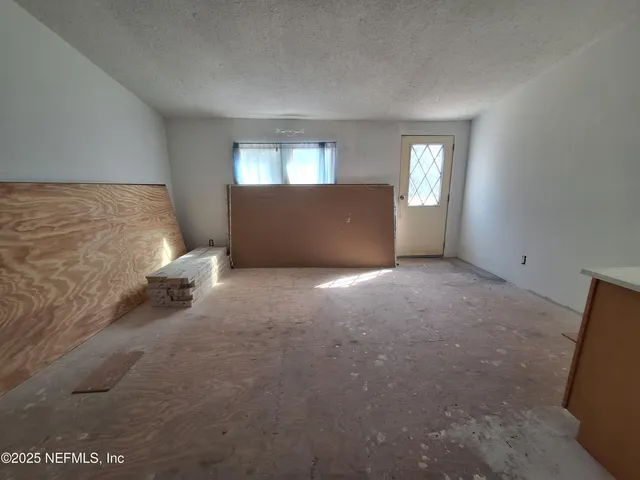 a view of an empty room with window and wooden floor