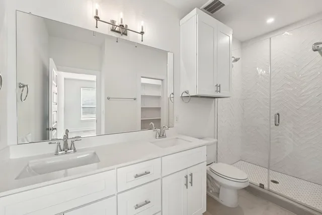 a bathroom with a double vanity sink toilet and shower