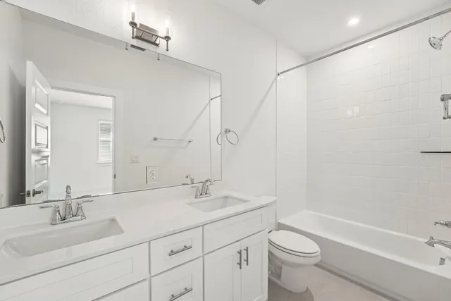 a bathroom with a double vanity sink toilet mirror and bathtub