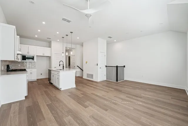 a kitchen with stainless steel appliances kitchen island wooden floors and white cabinets