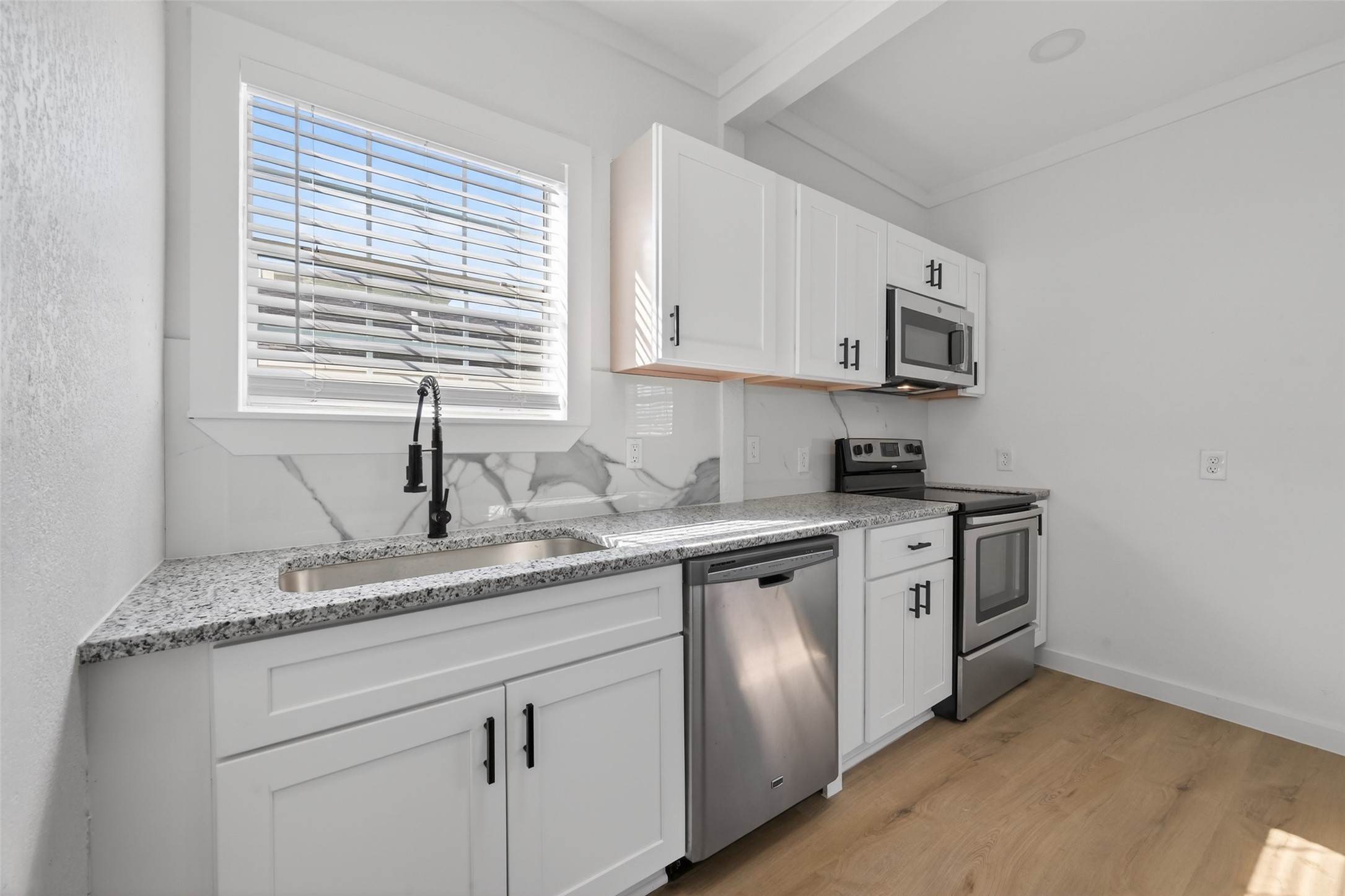 2202 Hutchins Street, Unit C Houston, TX 77003 - Photo 9 of 27 a kitchen with stainless steel appliances granite countertop a sink dishwasher a stove and a microwave oven with cabinets