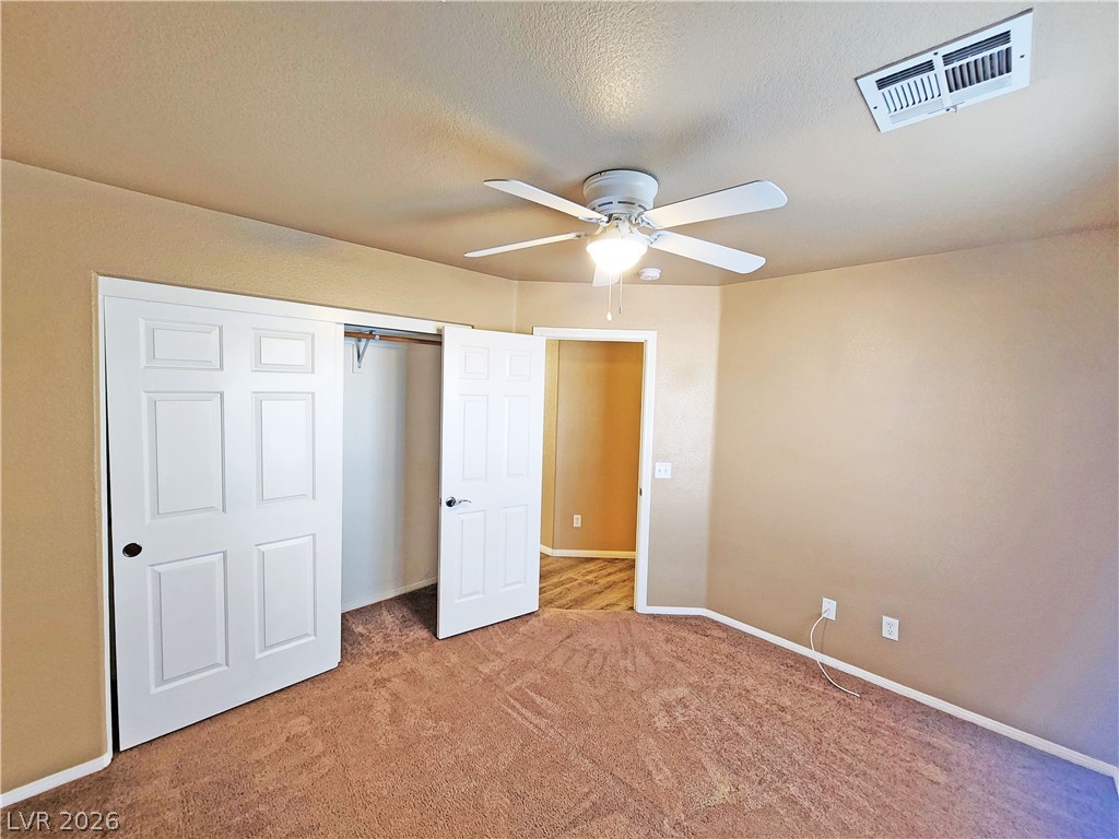 3680 Ravine Avenue Pahrump, NV 89048 - Photo 20 of 28 Unfurnished bedroom featuring baseboards, visible vents, light colored carpet, a ceiling fan, and a closet