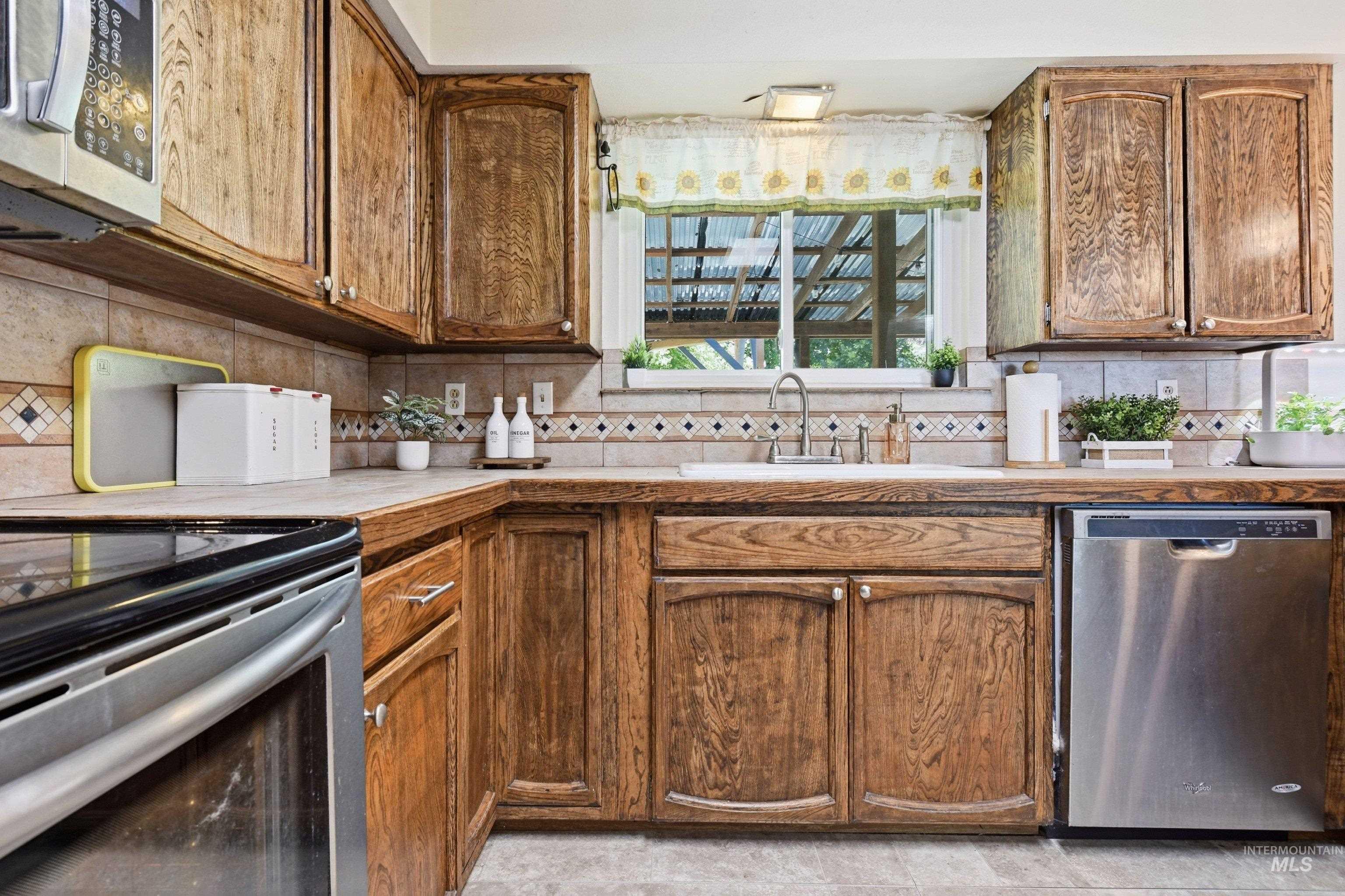 15095 David Street Caldwell, ID 83607 - Photo 16 of 39 Kitchen featuring wood cabinetry, stone countertops, a tile backsplash with decorative accents, a stainless steel dishwasher, and a built-in microwave