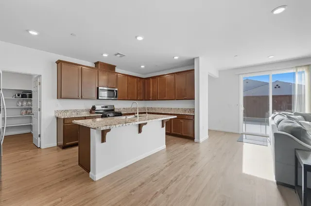 a kitchen with kitchen island granite countertop a sink cabinets and wooden floor