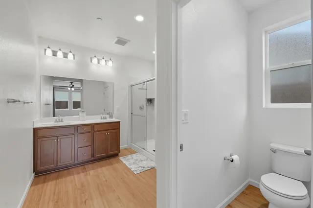 a spacious bathroom with a double vanity sink a large mirror and shower