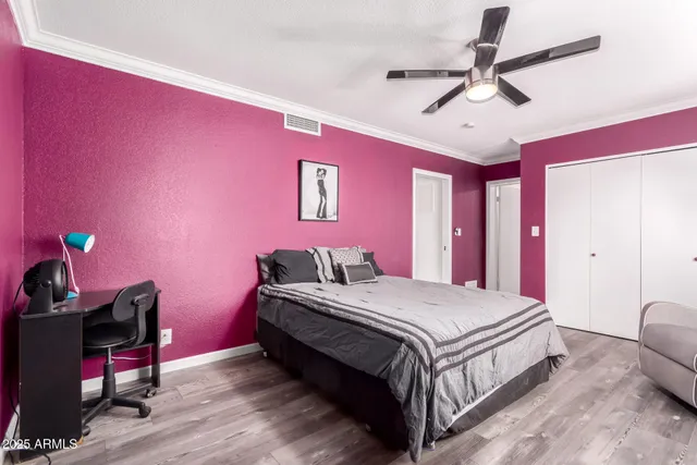 a bedroom with a bed a chandelier and pink walls