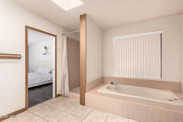 a spacious bathroom with a tub shower and bedroom view