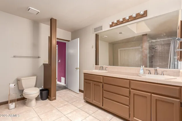 a spacious bathroom with a toilet sink double vanity and mirror