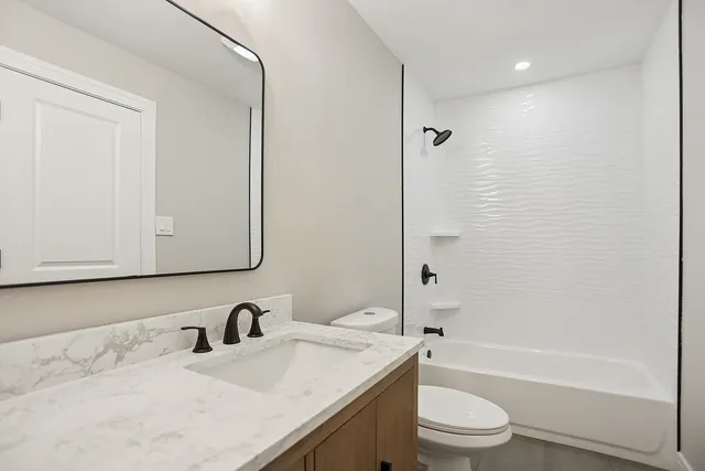 a bathroom with a granite countertop sink toilet and shower