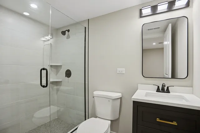 a bathroom with a toilet sink a mirror and shower
