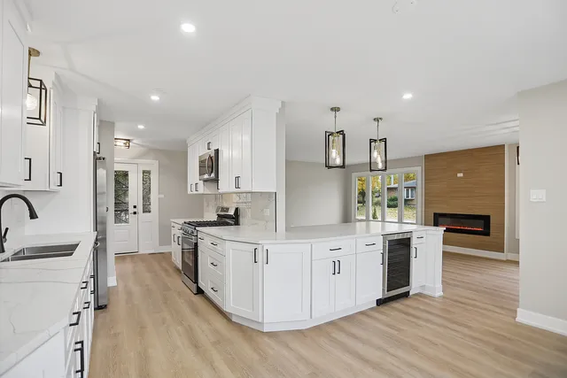 a kitchen with stainless steel appliances granite countertop a stove top oven a sink dishwasher and a refrigerator with wooden floor