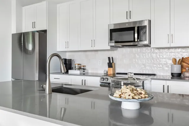 a kitchen with stainless steel appliances kitchen island granite countertop a sink a stove and a microwave