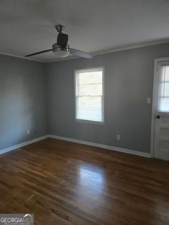 a view of an empty room with wooden floor and a window