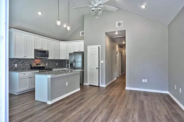a large kitchen with cabinets wooden floor and stainless steel appliances