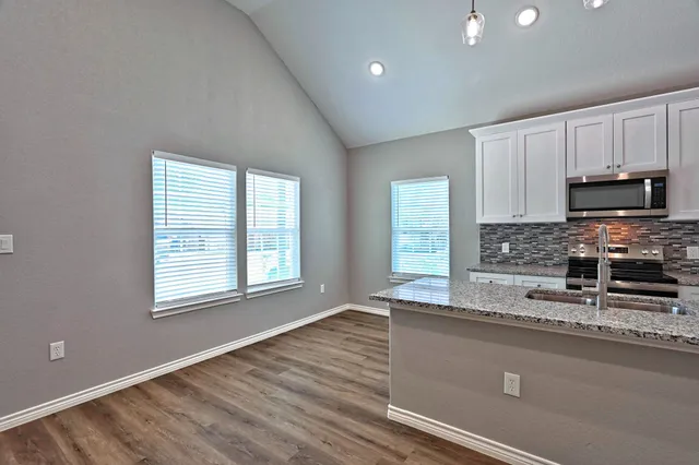 a kitchen with granite countertop a stove a sink and a microwave