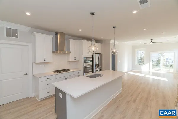 a kitchen with a sink a stove a refrigerator and white cabinets with wooden floor