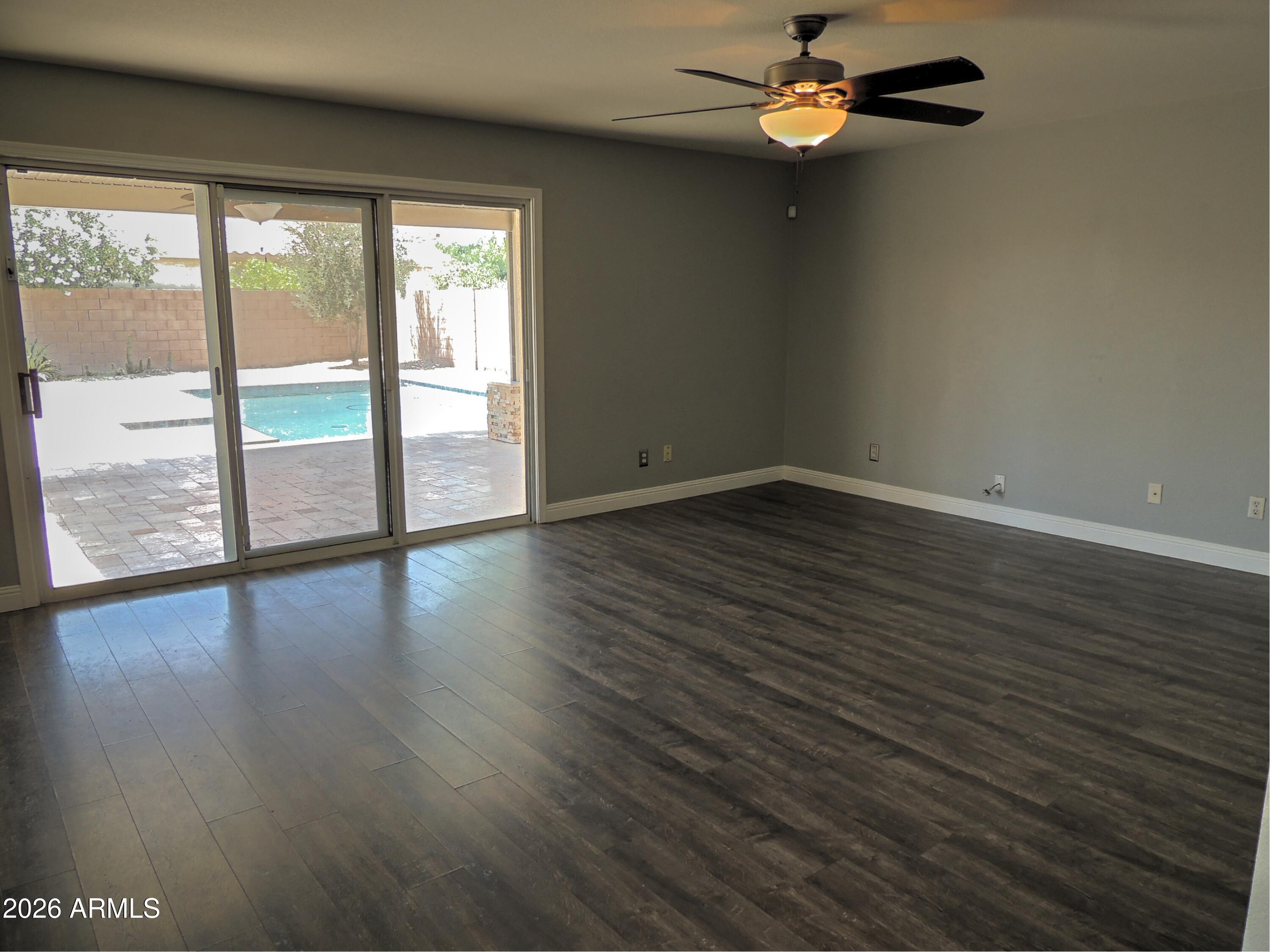 4409 East Dry Creek Road Phoenix, AZ 85044 - Photo 8 of 34 a view of an empty room with wooden floor and a window