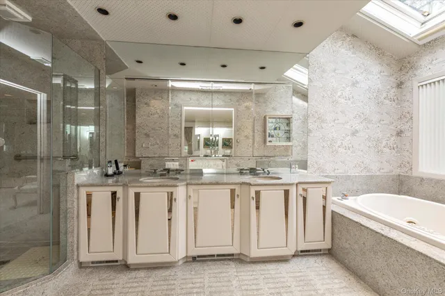 a bathroom with a granite countertop double vanity sink a mirror and a bathtub