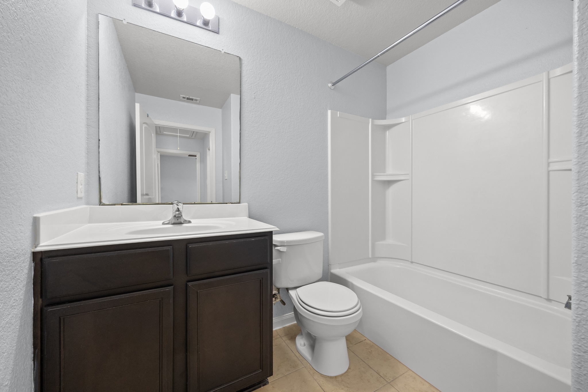 228 Millers Loop Jarrell, TX 76537 - Photo 18 of 26 Clean lines define this classic bathroom featuring a dark wood vanity and tiled flooring.