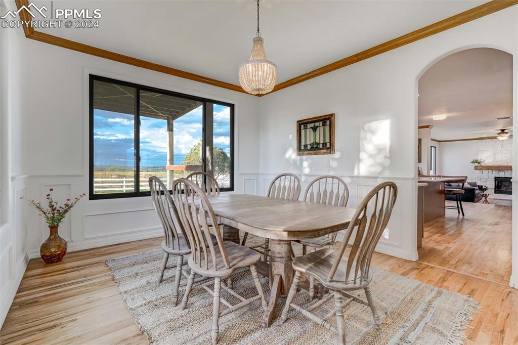 20880 Scott Road Calhan, CO 80808 - Photo 6 of 50 Dining space with light wood-type flooring, a stone fireplace, and ornamental molding