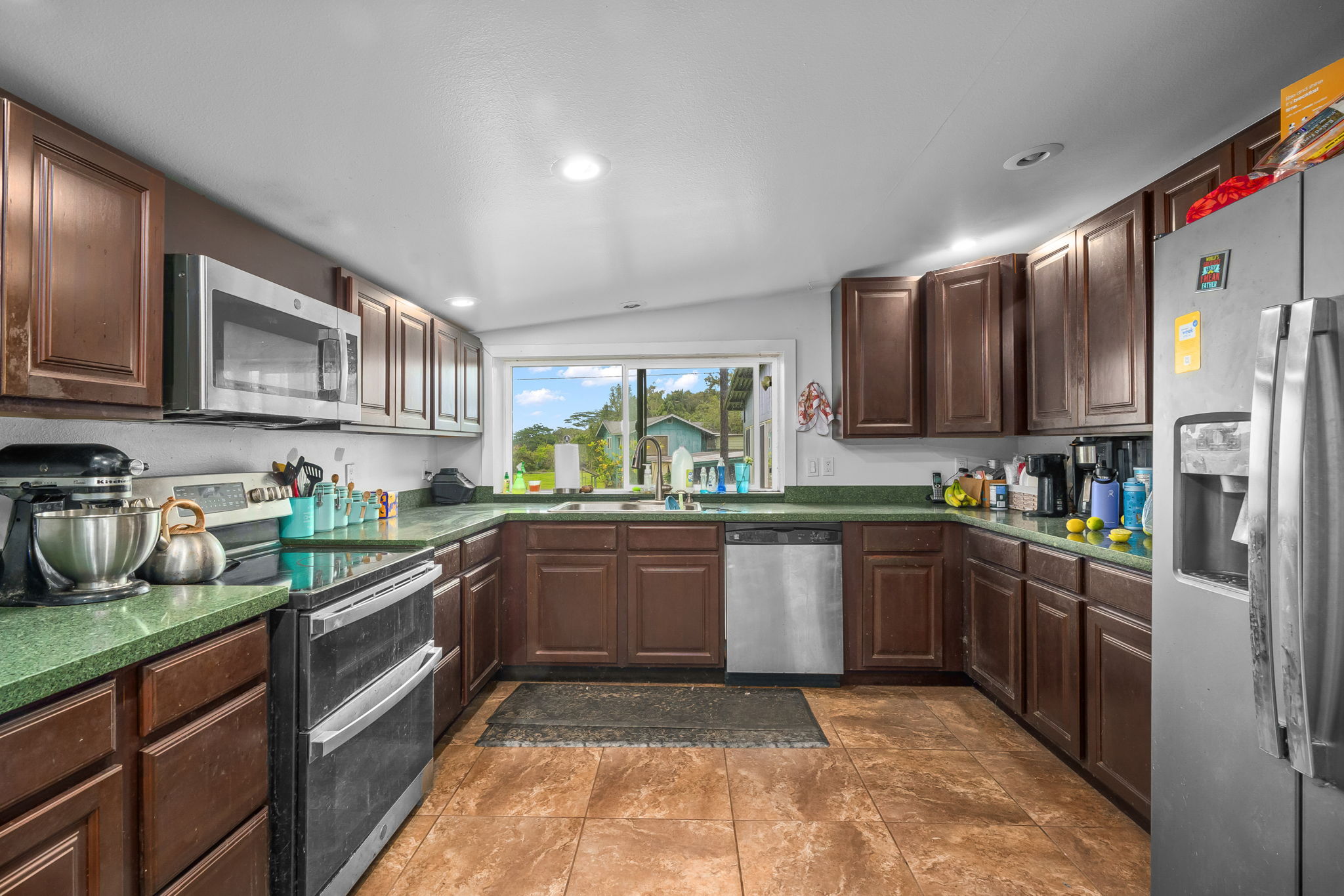 7060 Kahuna Road Kapaa, HI 96746 - Photo 7 of 25 a kitchen with stainless steel appliances granite countertop wooden cabinets a stove top oven a sink and dishwasher
