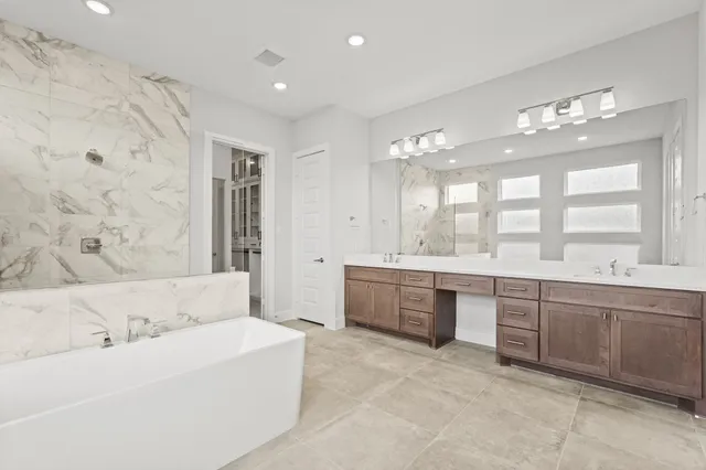 a large spacious bathroom with a double vanity sink a large mirror and a bathtub