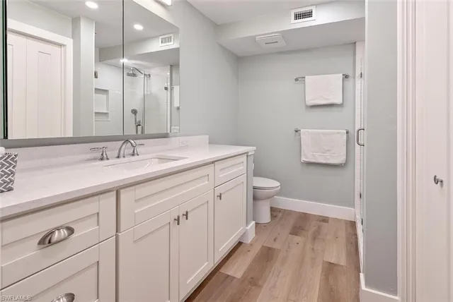 a spacious bathroom with a sink a toilet a shower and a mirror