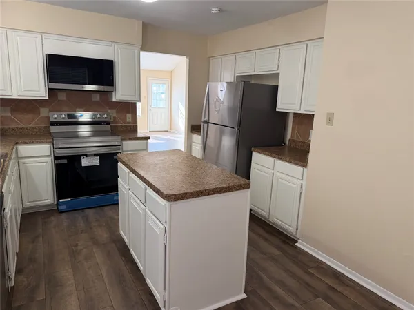 a kitchen with a refrigerator and a stove top oven