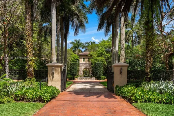 a view of a pathway with a fountain and plants