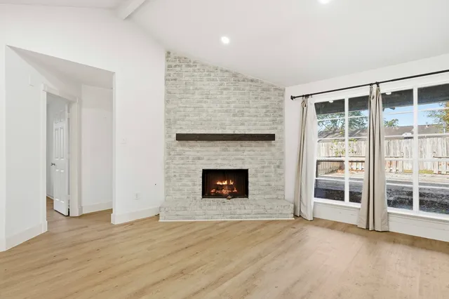 an empty room with wooden floor fireplace and windows