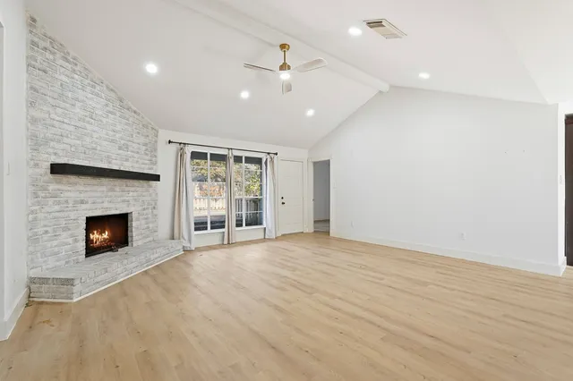 an empty room with windows and fireplace
